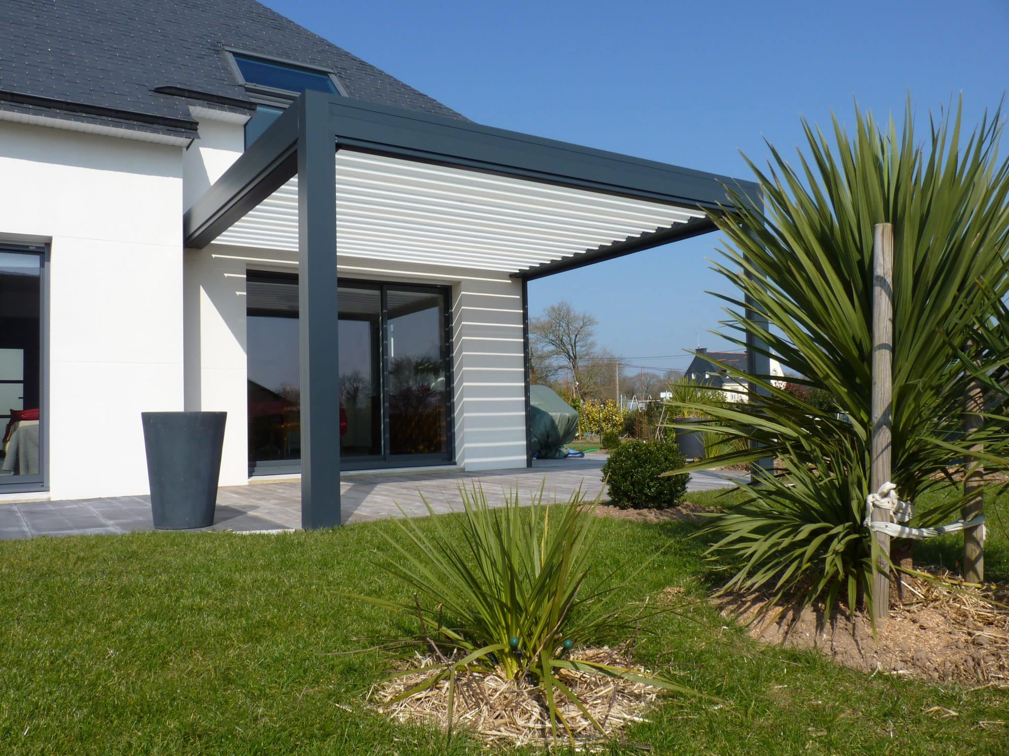 Une pergola bioclimatique à lames orientables permet d'avoir un espace entre l'intérieur et l'extérieur