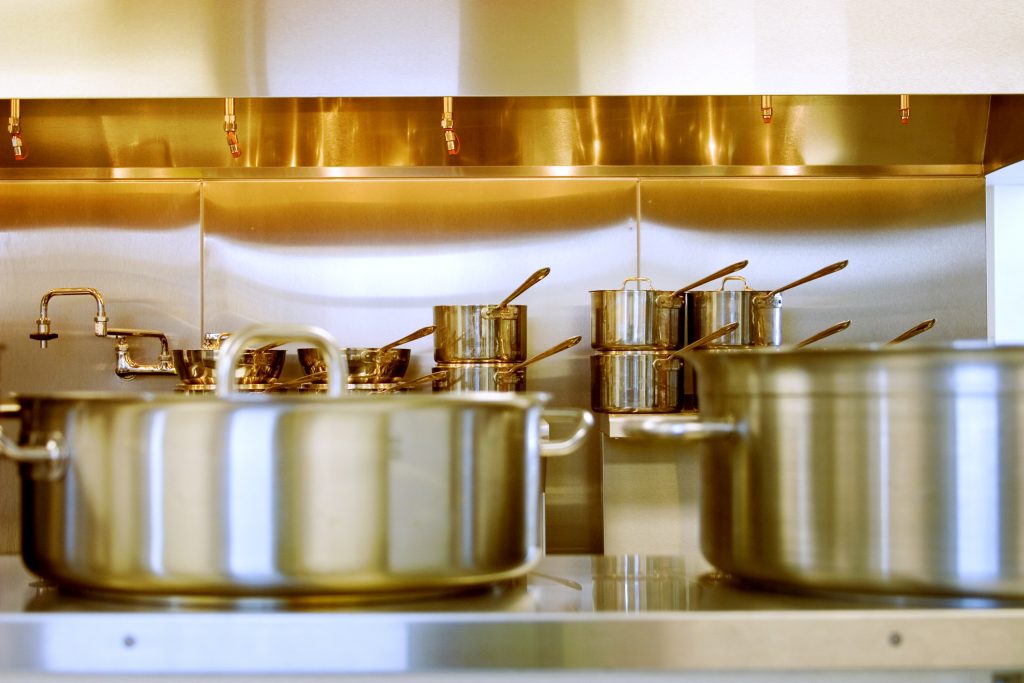 La cuisine d'un réstaurant avec une batterie de casserolles en inox